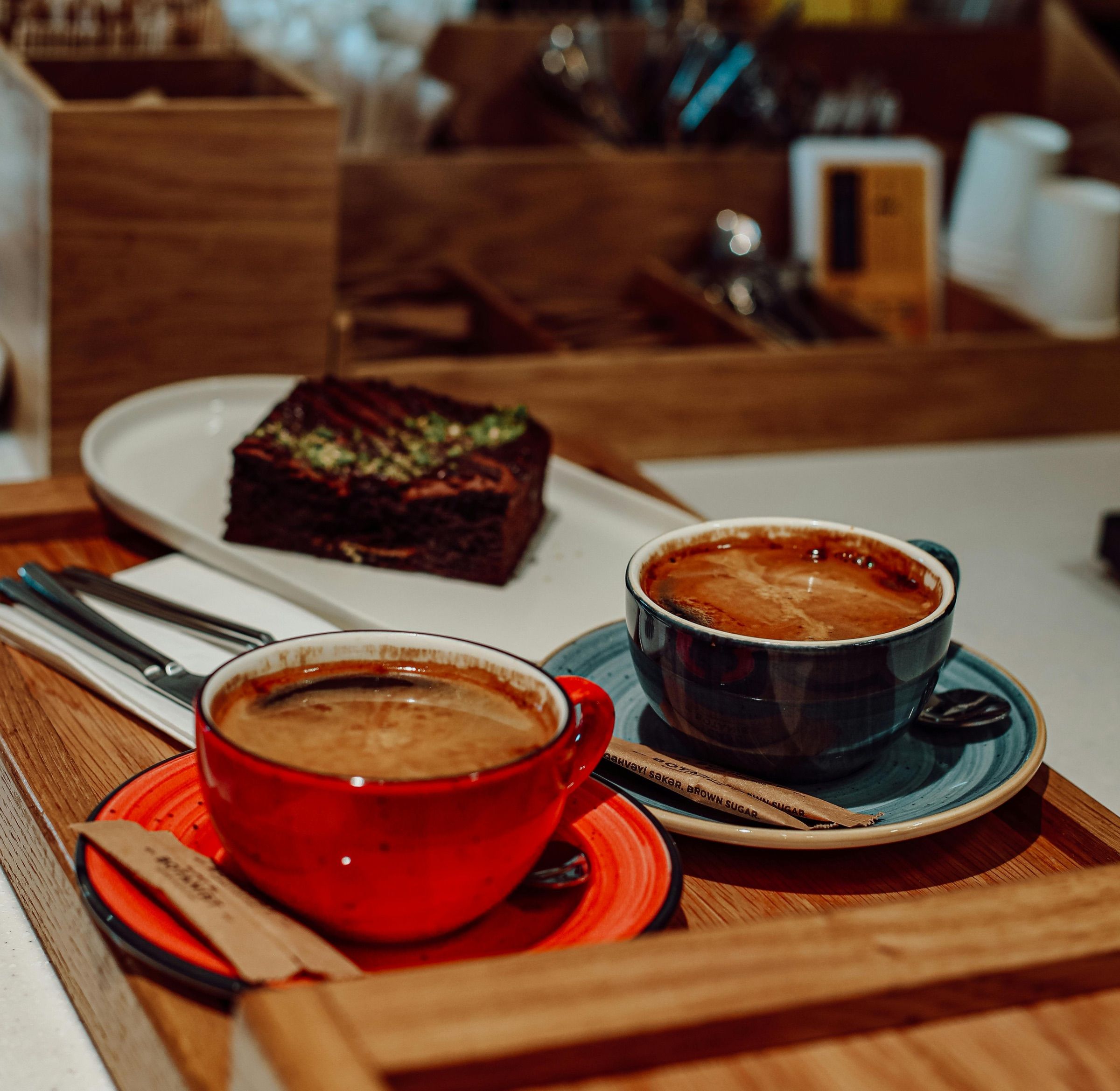 Deux cafés et un brownie sur un plateau en bois.