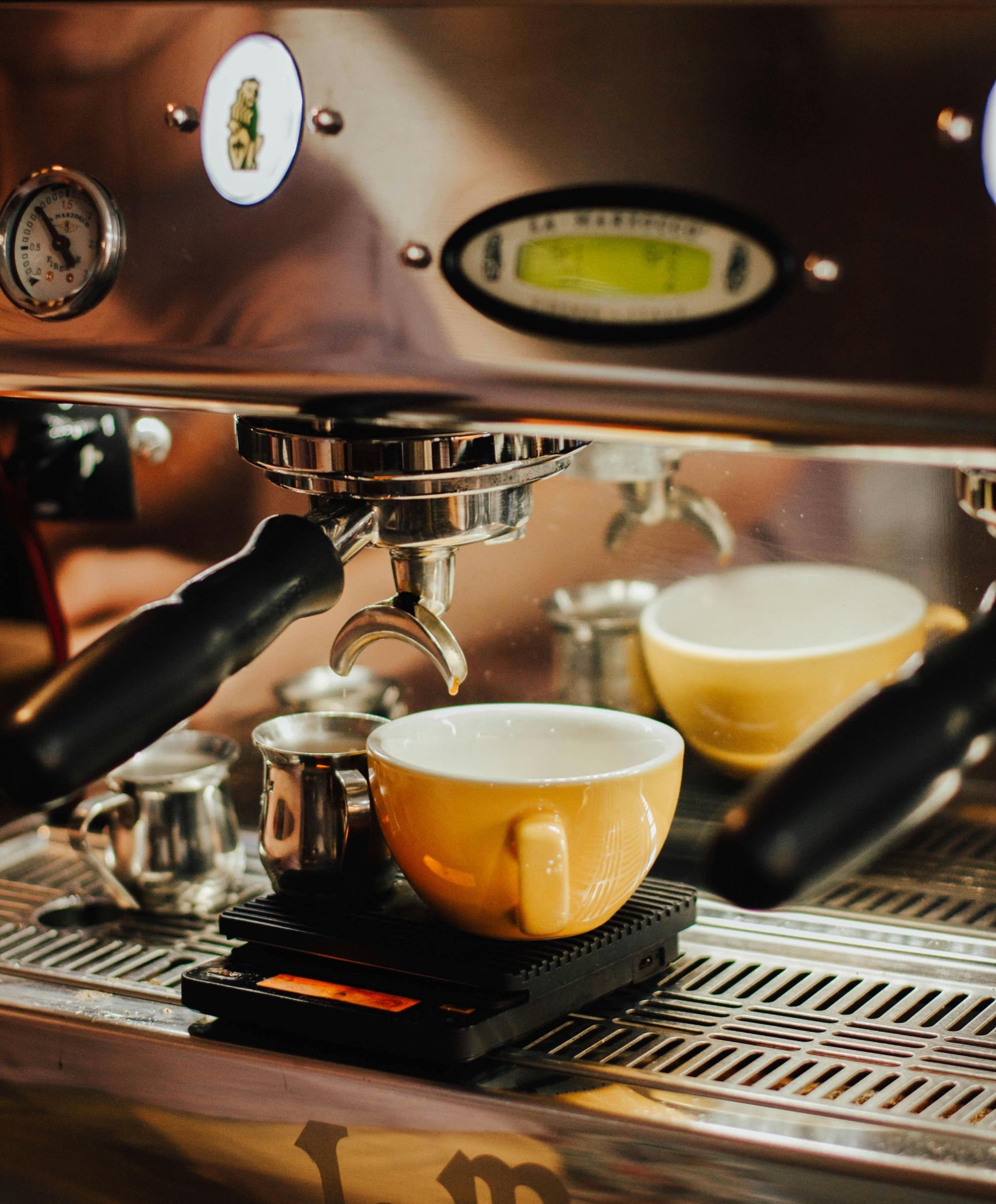 Deux tasses sous une machine à espresso.